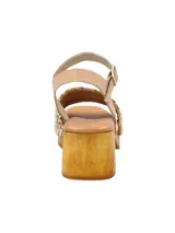 Sandalia de taco alto tipo zueco con plataforma de madera, capellada de rafia tejida multicolor, tira de ajuste al tobillo en cuero color tostado y tachas metálicas decorativas.