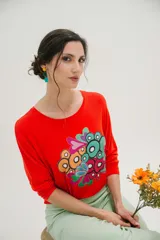 Remera roja de mangas largas con estampado abstracto de círculos y corazones en tonos celeste, verde, naranja y rosa.