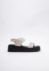 Sandalias color beige con plataforma negra de 4,5 cm, tira ancha sobre el empeine y tira con velcro ajustable alrededor del tobillo.