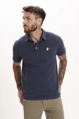 Remera tipo polo azul marino de manga corta con cuello clásico y cierre de dos botones. Presenta un pequeño bordado de un pájaro en el pecho.