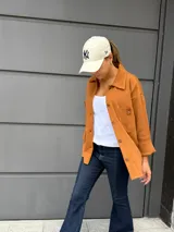 Camisa de punto color naranja quemado, con cuello camisero, botones frontales y bolsillos de parche en el pecho.