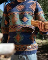 Buzo tejido de punto con diseño geométrico de estilo étnico. Presenta cuello redondo, puños y ruedo acanalados. Confeccionado en una mezcla de lana y fibras sintéticas, con etiqueta de marca en el pecho y en el ruedo.