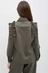 Camisa de manga larga color verde militar, con cuello clásico, cierre frontal de botones y detalle de volados en los hombros.
