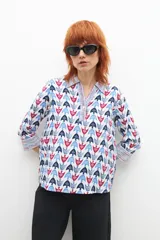 Blusa de manga larga con cuello camisero y estampado con motivos geométricos en tonos azul, rojo y blanco.