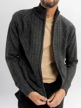 Campera tejida de punto en color beige, con diseño de trenzas y rombos, cuello alto y cierre frontal completo.
