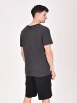 Remera color beige con estampa rectangular con diseño abstracto en tonos marrones y texto.