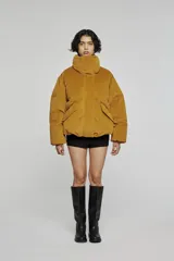 Chaqueta puffer de silueta corta y volumen amplio, con cuello alto envolvente, cierre frontal oculto y bolsillos laterales integrados.