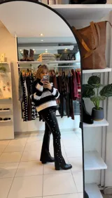 Pantalon de gabardina elastizada color negro, de corte ajustado con diseño de tachas metálicas plateadas a lo largo de las costuras laterales.