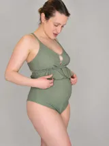 Malla enteriza maternal color verde salvia con tejido texturado, escote con aberturas y volado bajo el busto, de tiro alto diseñado para la etapa de embarazo.