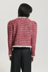Saco corto rojo con textura tweed y cuello con solapa con flecos blancos.