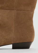 Bota de caña alta confeccionada en piel de serraje color marrón, con diseño plano, punta cuadrada y sin cierre.