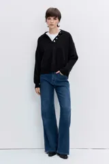 Sweater de punto negro con cuello polo y cierre frontal de botones, de manga larga y calce holgado.