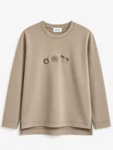 Buzo de cuello redondo en color beige, confeccionado en tejido jogging de algodón. Presenta bordados frontales con motivos de un mate, un sol y un caballo. Cuenta con diseño de ruedo asimétrico con aberturas laterales.