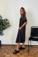 Vestido camisero largo color negro, de manga larga remangada, con cuello camisero y cierre frontal de botones. Corte amplio y falda con vuelo.