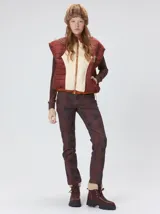 Chaleco de corte cuadrado con diseño bicolor en tonos terracota y crema. Presenta cierre frontal metalizado, parches de nylon en el pecho, interior forrado en corderito y cordón ajustable en el ruedo.