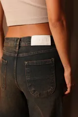 Pantalón de jean de tiro alto con lavado oscuro y detalles de desgaste.