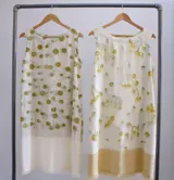 Vestido corto sin mangas, con estampado de hojas en tonos beige y verde, y falda color lila con detalle de flecos en el ruedo.