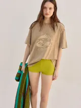 Remera oversize de corte cuadrado, color verde, con cuello redondo y estampa retro centrada en tono amarillo.