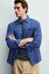 Camisa regular fit celeste confeccionada en mezcla de lino y algodón, con cuello abotonado, manga larga, bolsillo frontal en el pecho y cierre de botonadura.