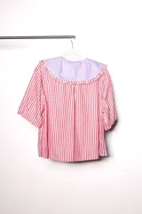 Camisa de lino texturado con diseño a rayas verticales rojas y blancas, cuello babero desmontable en color lila con volados y mangas cortas abullonadas.