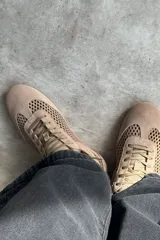 Championes de gamuza color tostado con diseño de paneles perforados en los laterales y empeine. Presentan cierre con cordones al tono y tirador en el talón.