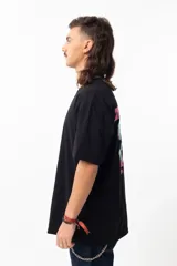 Remera negra de algodón con estampado en la espalda que dice "THE EARTH IS FLAT" y un dibujo de un hombre con micrófono parado sobre una tierra plana.