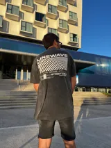 Remera negra con efecto gastado, corte amplio y estampado en la espalda con la palabra "Linewave" y un diseño de ondas blancas.