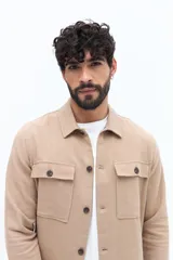 Sobrecamisa de hombre color beige, de líneas clásicas, con cuello camisero, botones frontales y dos bolsillos de parche con solapa en el pecho.