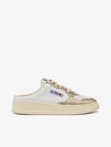 Zapatillas Autry Medalist Slip-On, estilo mule, color blanco y dorado, confeccionadas en cuero de becerro con perforaciones en la puntera.