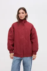 Campera bomber de gabardina con diseño capitoneado, cuello alto, cierre frontal con botones a presión ocultos y mangas abullonadas con puños elásticos.