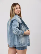 Campera de jean celeste con detalles de roturas, corte oversize, cuello clásico, cierre con botones metálicos, bolsillos frontales con solapa y puños abotonados.