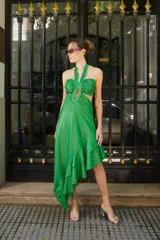 Vestido verde brillante, con escote halter anudado al cuello, aberturas laterales (cut-outs) y falda asimétrica con volados en el ruedo.