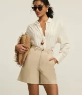 Bermuda color beige de sastrería, confeccionada en sarga de algodón, con cintura mediana, trabillas, cierre tradicional y bolsillos.