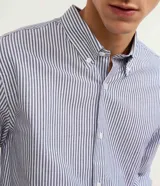 Camisa de vestir de hombre, corte regular, confeccionada en tejido Oxford rayado en tonos azul y blanco. Cuenta con cuello abotonado, manga larga con puños abotonados y cierre frontal con botones.