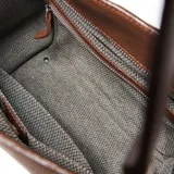 Cartera de hombro de cuero con diseño estructurado y base ancha. Presenta logo de la marca grabado en el frente y correas fijas.