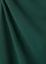 Vestido corto verde oscuro con cuello barco, manga larga y diseño entallado con fruncidos laterales.