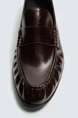 Mocasín de vestir para hombre en color negro, con acabado brillante, detalle de antifaz en el empeine y punta redondeada.
