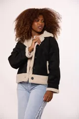 Campera tipo gamulán de gamuza color marrón con interior y solapas de corderito sintético color beige. Presenta cierre frontal con botones, mangas largas y corte holgado.