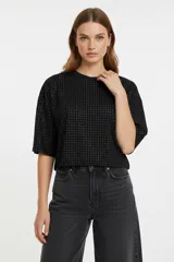 Remera negra de corte holgado con mangas 3/4 y cuello a la base, decorada con pequeños studs metálicos distribuidos por toda la prenda.