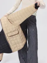 Campera reversible capitoneada con cierre frontal. Un lado es de color negro y el otro es de color beige, ambos con diseño acolchado. Cuenta con cuello redondo, mangas largas y bolsillos laterales.