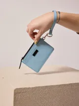 Billetera azul de poliuretano con cierre y correa de mano.