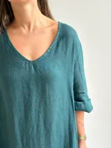 Vestido largo verde petróleo con estampado floral grande en tonos marrones y ocres, de corte amplio, mangas tres cuartos y escote en V.