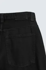 Jeans de denim de algodón color negro, con corte balloon fit relajado desde la cadera y ligeramente estrechado en el bajo. Tiro medio, cinco bolsillos y cierre frontal con cremallera y botón.