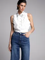 Camisa blanca sin mangas con cuello clásico, cierre frontal con botones y apliques de strass en cuello y frente.