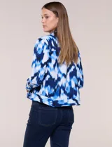 Camperita liviana de silueta entallada con estampado abstracto en tonos de azul y blanco, cuello camisero, cierre frontal con botones, bolsillos en el pecho con solapa y mangas largas.