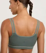 Top deportivo sin costuras color verde musgo, con doble tirante y banda elástica inferior con dos rayas horizontales claras. Posee relleno removible.