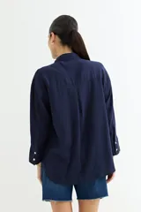 Camisa color beige de corte amplio, con cuello clásico, manga larga y bolsillo en el pecho.