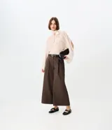 Pantalón pantacourt de sastrería color marrón, con corte amplio, largo midi y pinzas frontales. Incluye cinturón con hebilla metálica y bolsillos traseros embutidos.