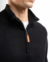 Buzo de tejido de punto negro, con cuello alto y cierre frontal parcial.