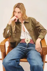 Campera de estilo militar color verde oliva, con corte regular, bolsillos frontales tipo plaqué y cierre frontal con botones metálicos.